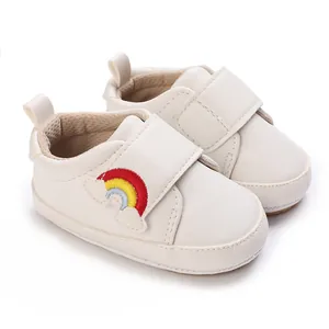 Detailweergave van witte baby-loop schoenen met regenboogborduurwerk en een zachte zool