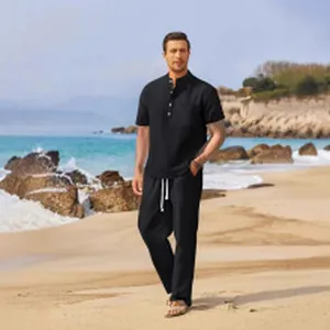 Full-length view of men's casual black Henley shirt and matching trousers on a beach.