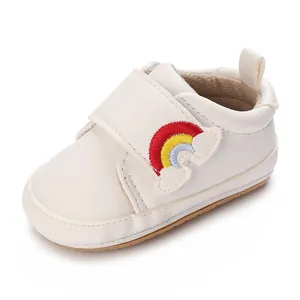 Gedetailleerd beeld van witte baby loopschoen met zachte zool en regenboog borduurwerk