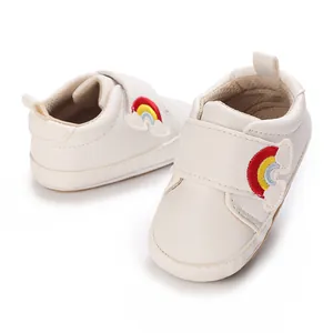 Detail van gebroken witte baby loopschoentjes met regenboogborduursel en een zachte zool