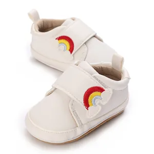 Detailopname van beige baby-loopschoenen met kleurrijk regenboogborduurwerk en zachte zool