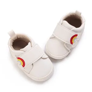 Witte babyloopschoenen met regenboogborduurwerk en klittenband op witte achtergrond