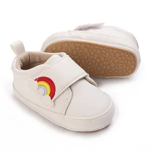 Detail van witte leren baby-loopschoenen met zachte zool en kleurrijke regenboogborduring