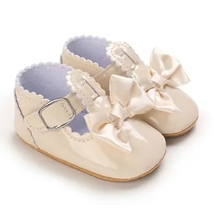 Nahaufnahme von Baby Mädchen Lauflernschuhen aus beigem Lackleder mit Schleife