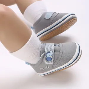 Dettaglio scarpe da bambino grigie con suola morbida e chiusura a strappo con elefante.