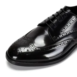 Gros plan sur les motifs brogue complexes des chaussures en cuir noir poli pour homme