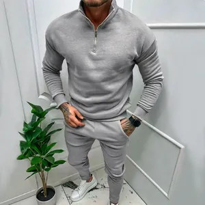 Full view of grey men's quarter-zip tracksuit set worn by model in casual indoor setting.