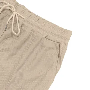 Dettaglio ravvicinato di pantaloncini beige casual da uomo con elastico in vita e trama fine