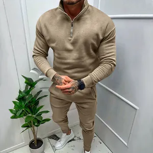 A male model wearing a stylish khaki two-piece fleece tracksuit with a quarter-zip sweatshirt.
