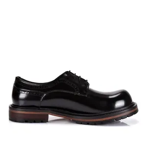 Detalle lateral de zapatos Derby de cuero negro con troquelado brogue y suela gruesa.