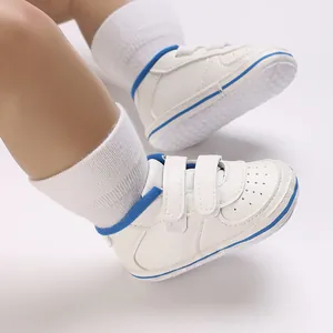 Detailed view of white baby walking shoes with blue trim and velcro straps