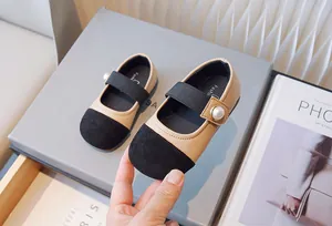 Primer plano de zapatos Mary Jane beige y negros para niña con detalle de perla.
