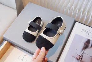 Primer plano de elegantes zapatos Mary Jane beige y negros con perla para niñas