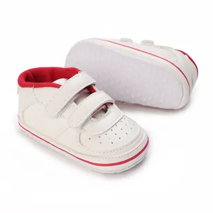 Detail view of white infant walking shoes with anti-slip rubber sole and velcro straps