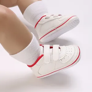 Detail view of white baby walking shoes with red trim and non-slip soles on a baby doll