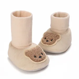 Vue détaillée de bottines en coton pour bébé beiges avec un patch ours en peluche mignon.