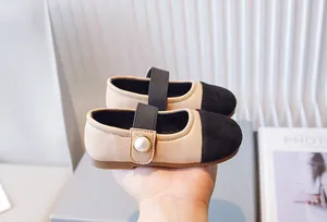 Vista detallada de zapatos Mary Jane beige y negros para niña con un elegante detalle de perla