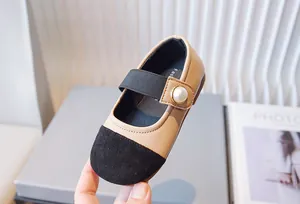 Detalle de zapatos Mary Jane beige para niñas con puntera negra y detalle de perla
