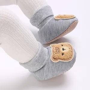 Gros plan de chaussettes de marche bébé grises avec ours en peluche et semelle