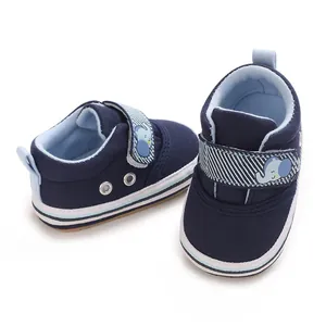 Dettaglio di scarpe di tela blu navy per neonati con cinturino a strappo con elefante.