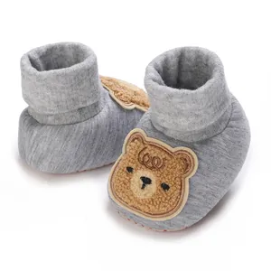 Gros plan d'un patch d'ours sur des chaussons de bébé en tricot gris