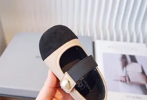 Primer plano de zapatos Mary Jane para niñas en beige y negro con botón de perla