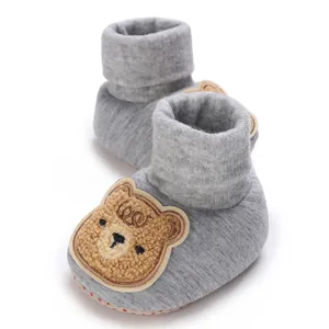 Vue détaillée de chaussons gris pour bébé en coton doux avec un joli patch ours