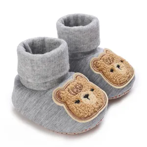Gros plan détaillé de chaussures de marche pour bébé grises avec écusson ours mignon