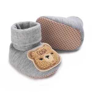 Gros plan de chaussures de bébé grises avec patch ourson et semelle antidérapante