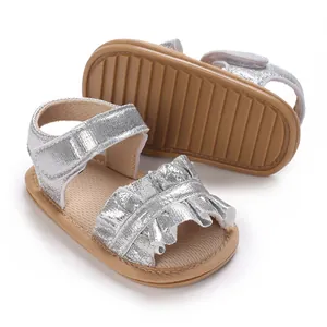 Detail view of shiny silver baby girl sandals with ruffles and non-slip soft soles
