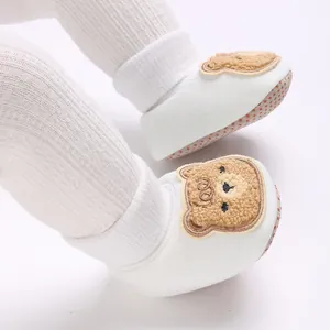 Gros plan sur le motif ours en peluche mignon des chaussures de marche souples bébé.