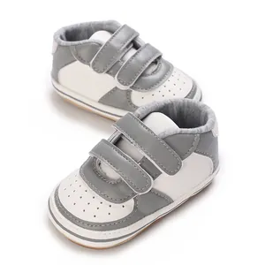 Gros plan de baskets pour bébé gris et blanc avec bandes Velcro et semelle souple.