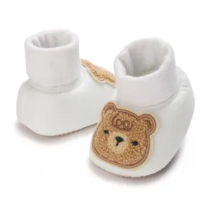 Vue détaillée de chaussures pour bébé blanches avec un motif d'ours en peluche mignon