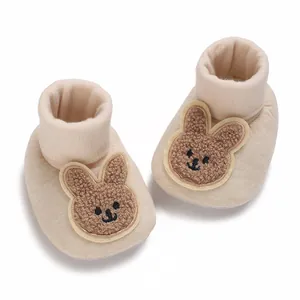 Vue détaillée de chaussures pour bébé beiges avec broderie lapin en peluche