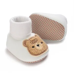 Détail des chaussures de marche pour bébé avec écusson ourson et semelle antidérapante