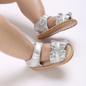 Silver glitter baby sandals with ruffles and soft sole worn by a model doll