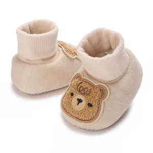Détail des chaussures de marche pour bébé beiges avec un motif de patch d'ours mignon