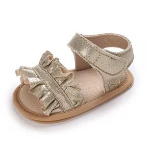 Close-up of gold ruffled baby sandals with soft non-slip soles for infant girls.