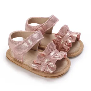 Detailed view of pink sparkly baby girl sandals with ruffles and soft soles walking shoes.