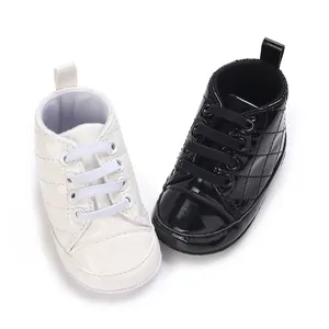 Nahaufnahme von hochgeschnittenen Baby-Lauflernschuhen aus schwarzem und weißem Lackleder