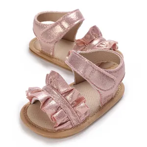 Detail view of pink metallic baby girl sandals with ruffles and soft non-slip soles.