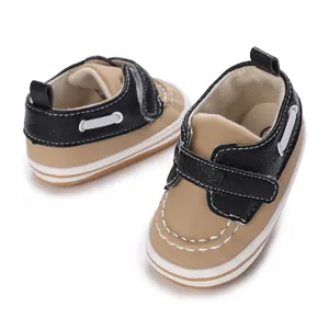 Nahaufnahme von hellbraunen und schwarzen Baby-Lauflernschuhen mit Ziernähten