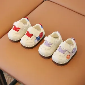 Scarpe primi passi neonato con suola morbida, lacci colorati e dettagli di badge smiley.