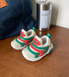Close-up van ademende baby rups schoenen met rode en groene accenten op hout