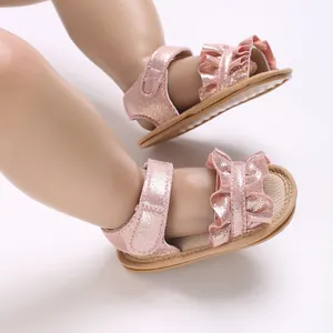 Close-up view of pink sparkly baby princess sandals with ruffle detail and soft soles.