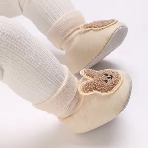 Détail de jolies chaussures de marche bébé beige avec oreilles de lapin en peluche