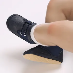 Dettaglio di scarpine sportive blu navy per neonato con trama in pelle morbida.