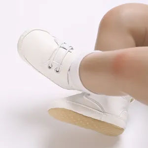 Dettaglio delle scarpe primi passi bianche per neonati con suola antiscivolo morbida.