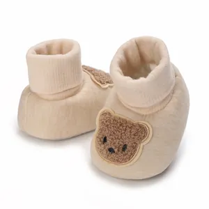 Chaussons souples beiges pour bébé avec écusson ourson pour nourrissons de 0-12 mois.