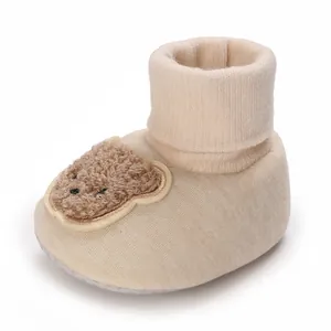 Gros plan sur un joli chausson pour bébé beige avec un écusson d'ours en peluche